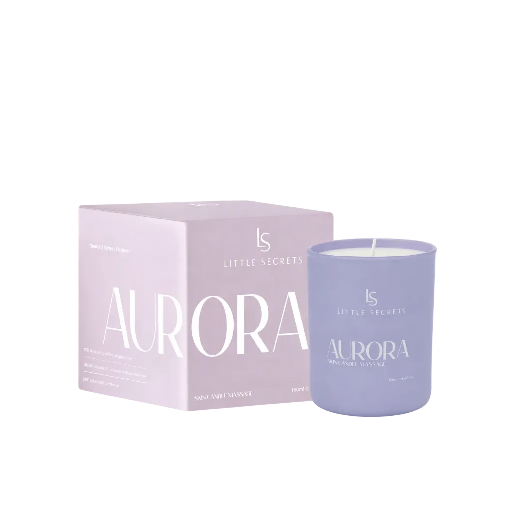 A lavender purple soy candle in a matching glass jar next to its light pink packaging box, both featuring the 'Little Secrets Aurora' branding.