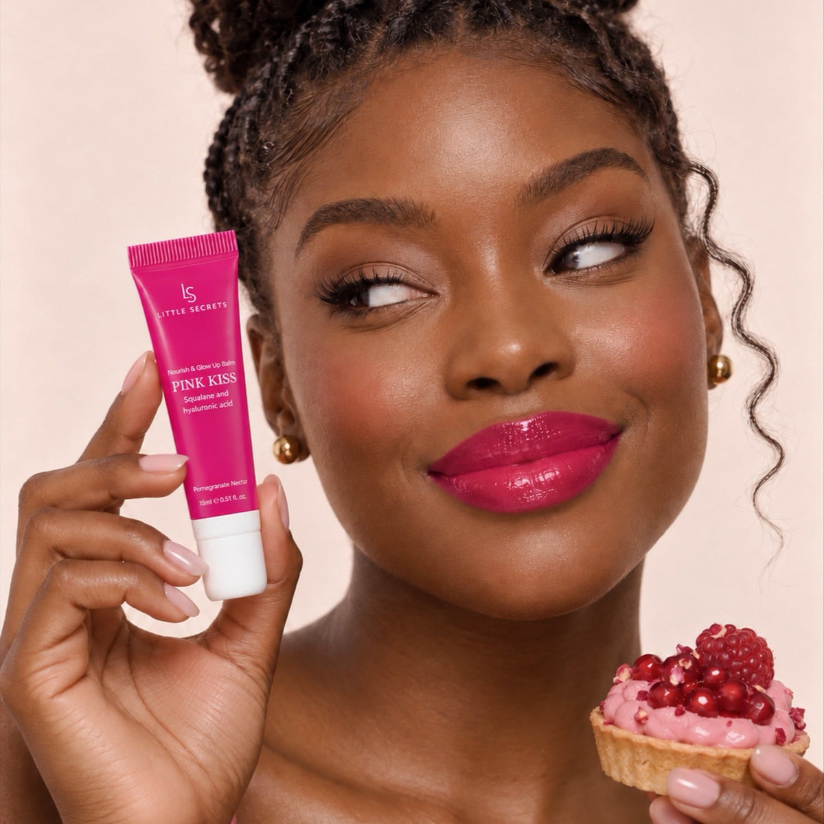 A woman with braided hair holds a pink cosmetic tube labeled 'ls style beauty PINK KISS' in one hand and a small pink tart topped with berries in the other, against a soft beige background.